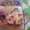 Pink Grey leaf purse 3x4 Handmade vintage-style floral coin purse with an antique bronze kiss-lock clasp, resting on a wooden table beside a dusty pink rose and a ceramic vase.