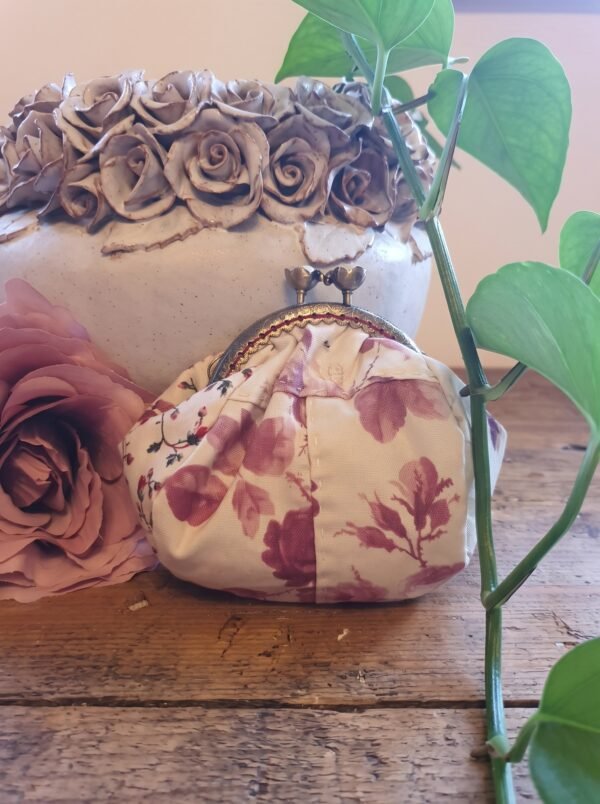Pink Grey leaf purse 3x4 Handmade vintage-style floral coin purse with an antique bronze kiss-lock clasp, resting on a wooden table beside a dusty pink rose and a ceramic vase.