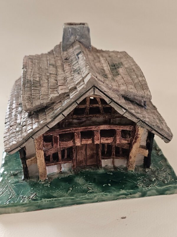 Handbuilt ceramic Tudor-style timber cottage with tiled roof, chimney and green base